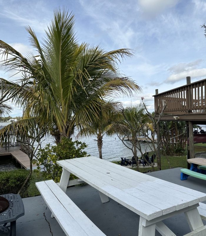 Photo of Picnic Tables on the Courtyard on the Left of the House with the Fire Pit and Dock in the Background