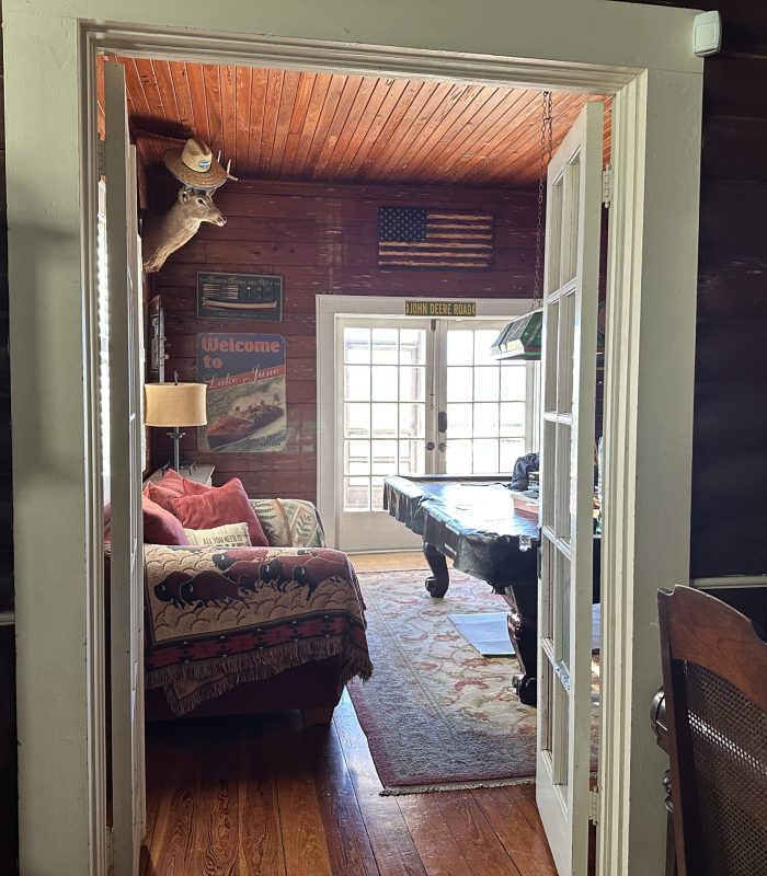A Photo of the Doorway Leading from the Living Room to the Pool Room with an Antique Grandfather Clock and Antique Piano in the Foreground